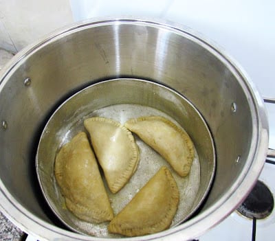 Four meat pies in a baking pan sitting inside a pot